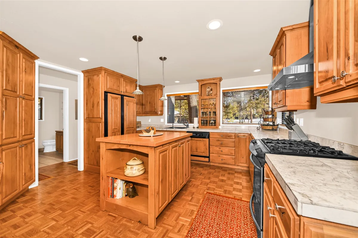 A cozy kitchen with a central island, plenty of wooden cabinetry, and a window view that brings in natural light. The design suggests functionality and warmth, ideal for both quick snacks and more elaborate meal preparation.
