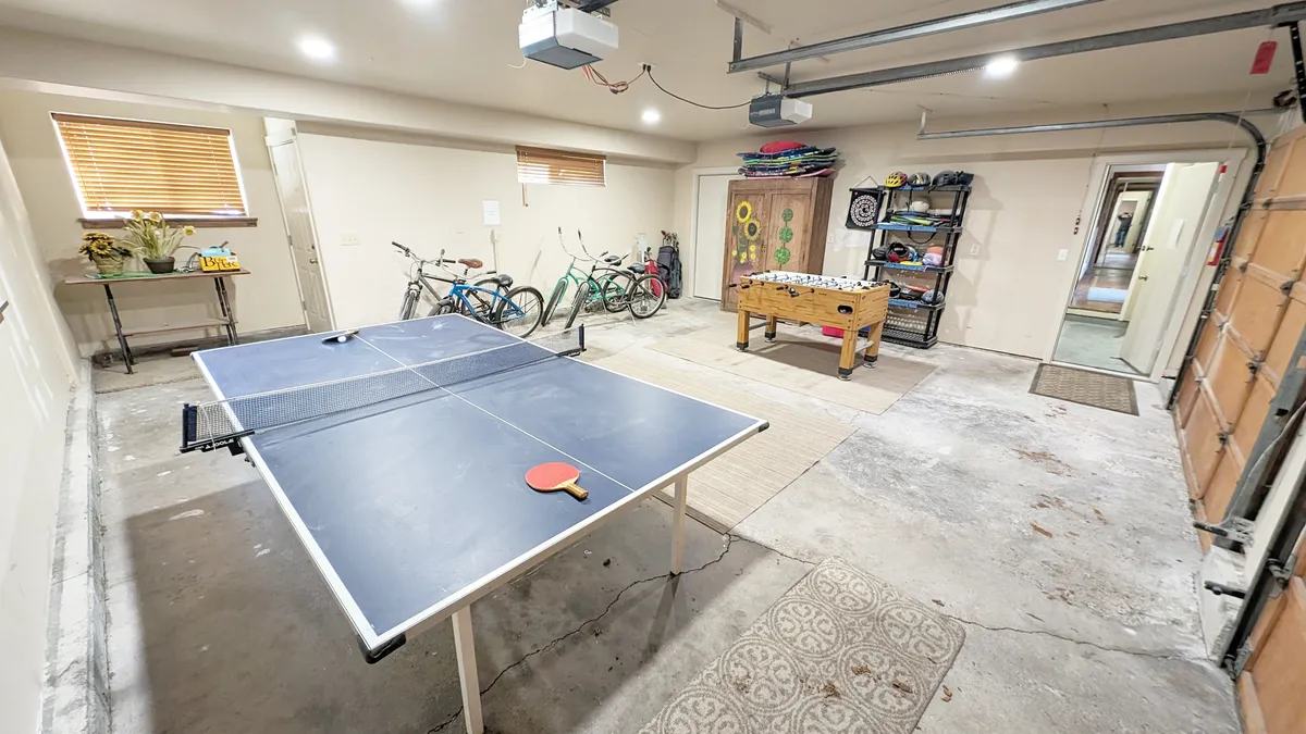 An inviting game room setup with a ping pong table, foosball table, and bicycles in the corner, accented with playful decor. The space is lively and designed for group fun, appealing to both kids and adults.