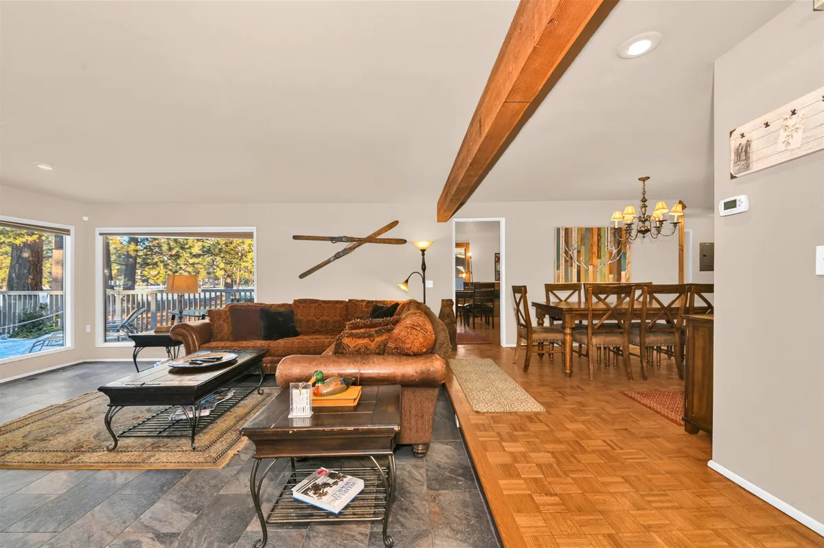 An expansive, open-concept area with a large sectional sofa, wooden dining table set for a crowd, and artistic wall decor. The atmosphere is warm and festive, ideal for family meals, group celebrations, or casual lounging.