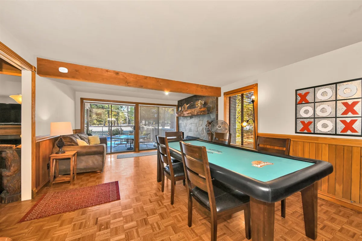 A sociable game room with a pool table, sliding glass doors, and wooden beams overhead. The area is set up for casual gatherings, game nights, and relaxed fun with family and friends. Natural light streams in, and the doors hint at easy access to outdoor amenities like the hot tub or pool.