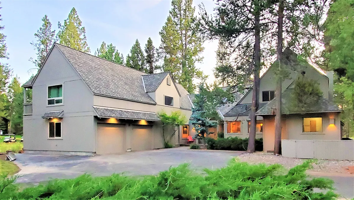A welcoming two-story home nestled among mature trees, with a landscaped front yard and a spacious garage. The serene setting hints at a connection to nature and opportunities for family gatherings or outdoor relaxation.