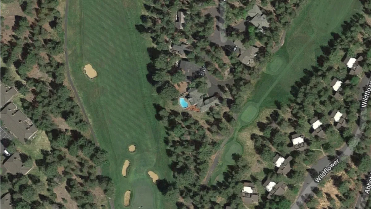 This image captures a sweeping view of the golf course with the private swimming pool in the foreground, surrounded by trees and nearby residential homes. The scene exudes a relaxed, summery vibe inviting viewers to imagine themselves swimming or gathering outdoors on a sunny day.